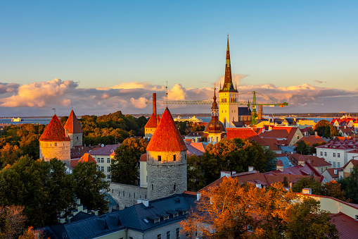 Classic Tallinn cityscape with Saint Olav's church and old town walls and towers at sunset, Estonia