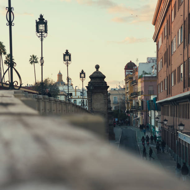 fotografia di strada di siviglia. strade tipiche di siviglia al tramonto. persone che camminano per la città viste da un ponte. la città andalusa di siviglia. - seville spanish culture spain town square foto e immagini stock