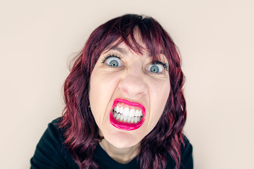 A funny fisheye photo of a 50 year old woman in rage showing her teeth.