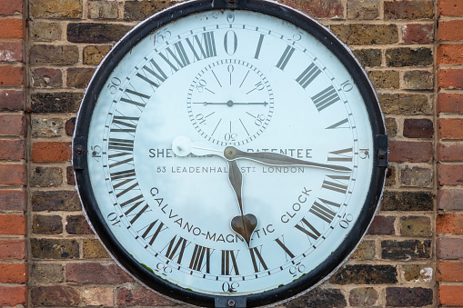 On the stone wall of a village an antique outdoor clock.