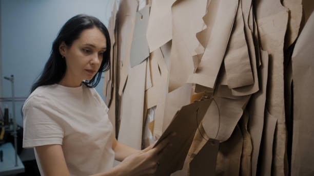 istock Dressmaker takes bunch of patterns from rack 1455816397
