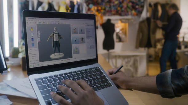 Designer creates 3D clothes on laptop in atelier