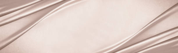 Beige cream silk satin. Draped fabric. Luxury background with space for design. Flat lay, top view table. Wide banner.
