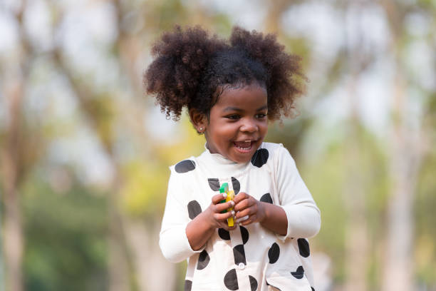 афроамериканская счастливая маленькая девочка играет на свежем воздухе в парке. девочка развлекается на свежем воздухе. чернокожие дети н� - little girls nature teenage girls small стоковые фото и изображения