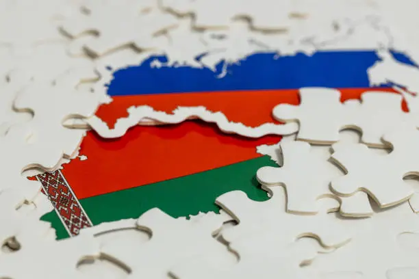 Photo of Flags of Russia and Belarus among scattered puzzle pieces, Concept of Geopolitical puzzle, military and economic alliance of both countries