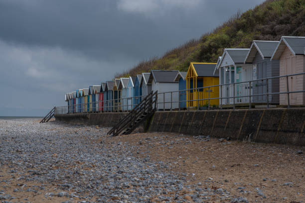 istock A row of brightly painted beach huts on a shingle beach in England 1455825817