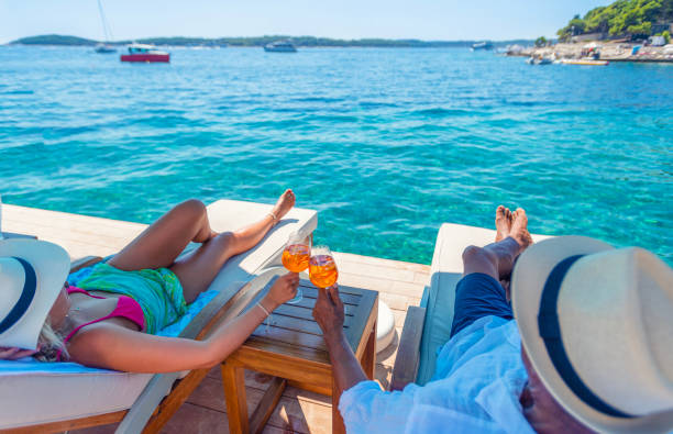 para relaksuje się i wznosi toast koktajlem aperol spritz na tarasie plażowym nad oceanem - chorwaci zdjęcia i obrazy z banku zdjęć