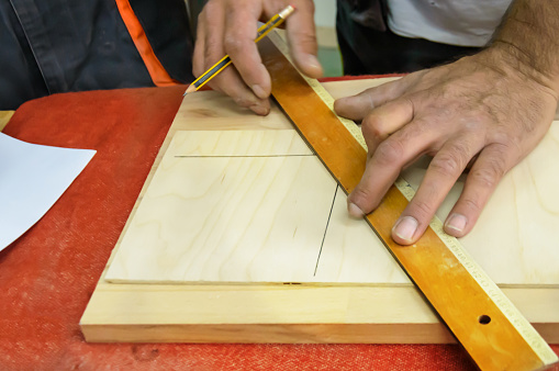 Close-Up Photo of Carpentry Worker who is Using a Ruler to Prepare Plank for a Woodwork.