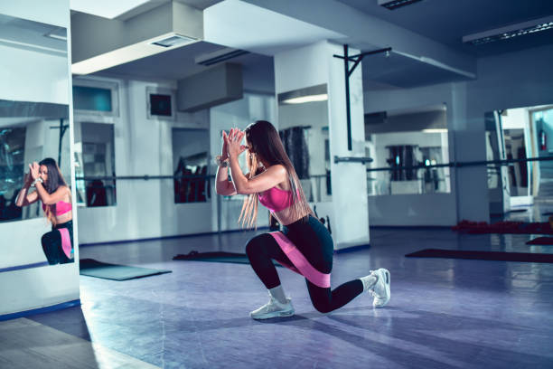 istock Female Making Lunges With Exercise Band In Gym 1455828700