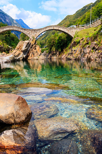 Antiguo puente romano de piedra de doble arco (Ponte dei Salti) sobre el agua clara del río Verzasca en Lavertezzo, Valle de Verzasca, Cantón del Tesino, Suiza photo
