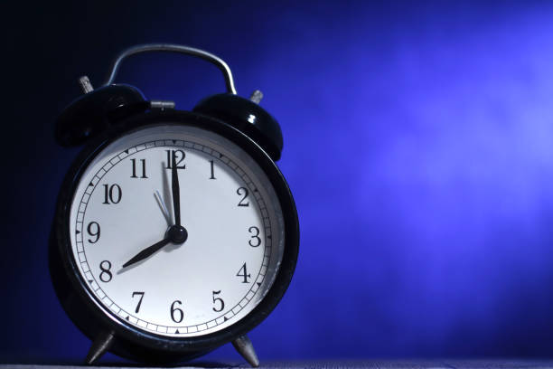 istock Time concept, alarm clock low angle view in the dark with blue copy space 1455835251