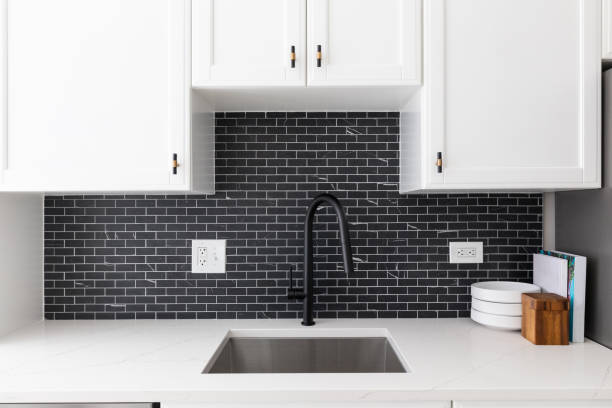 istock A kitchen sink detail with white cabinets and black subway tiles. 1455836062