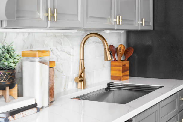 istock A gold kitchen faucet detail with grey cabinets. 1455836098