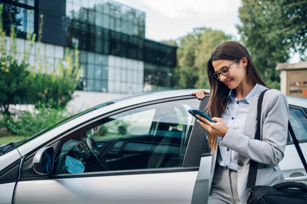 istock Business woman getting into the car and using smartphone 1455836552