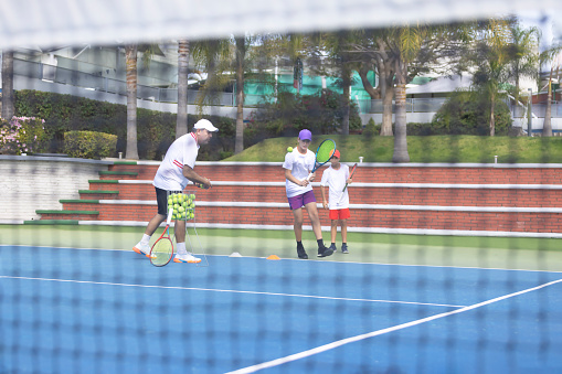 Coach and tennis players in training