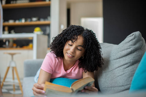 istock Happy woman reading book at home 1455849515