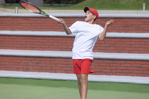 Boy training for tennis while grimacing