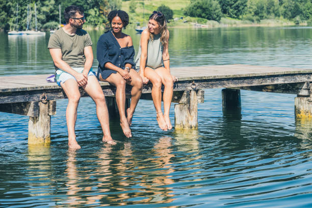 istock Friends having nice chilled conversation while sitting on a wooden pier with feet dangling down 1455850016