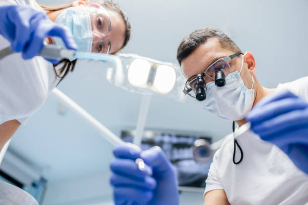 istock Dentist and female dental assistant holding dental tools. 1455851895