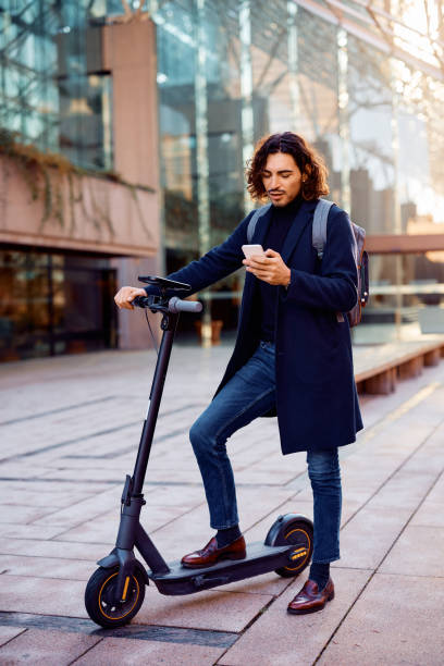 istock Latin American entrepreneur texting on smart phone while using electric scooter on the street. 1455853294