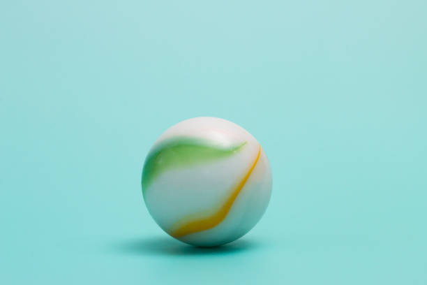 Toy marble on an aqua colored background stock photo
