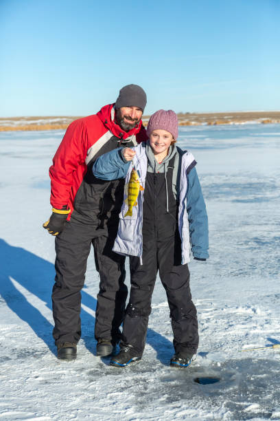 istock Girl Holding Up Perch She Just Caught While Ice Fishing 1455854392