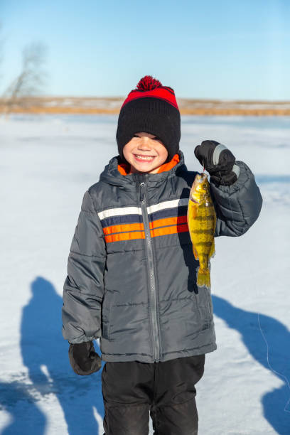 istock Boy Holding Up Perch He Just Caught While Ice Fishing 1455855355