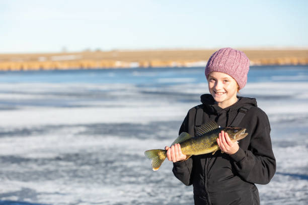 Girl Holding Up Walleye She Just Caught While Ice Fishing stock photo