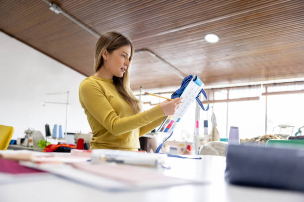 istock Seamstress looking at a fabric swatch at her atelier 1455864814