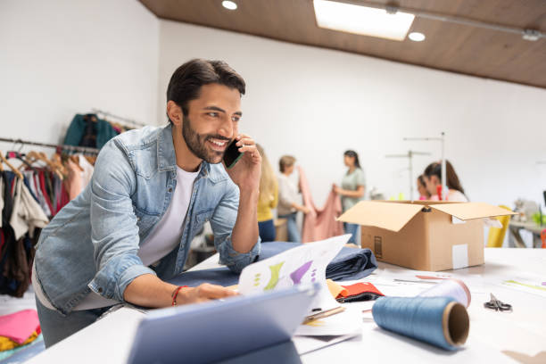 istock Fashion designer talking on the phone while working at his atelier 1455864849