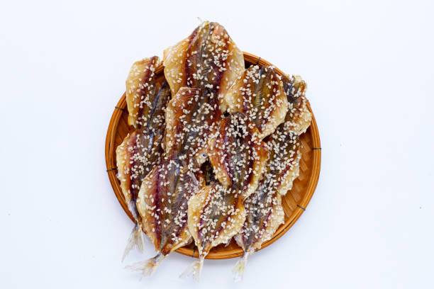 Dried fish with sesame seeds on white background.