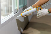 Construction worker using silicone sealant caulk the outside window frame.