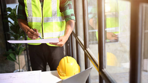 istock Professional Asian male construction engineer in uniform checking plan on a blueprint. cropped 1455880173