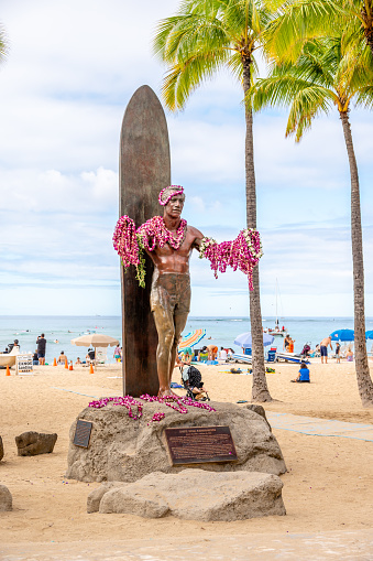 Honolulu, Hawaii - January 1, 2023: Duke Kahanamoku statue in front of Kuhio Beach Park in Waikiki was a Native Hawaiian competition swimmer who popularized the ancient Hawaiian sport of surfing