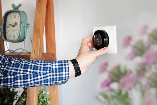 Man is Adjusting a  temperature  on the thermostat in the living room. stock photo