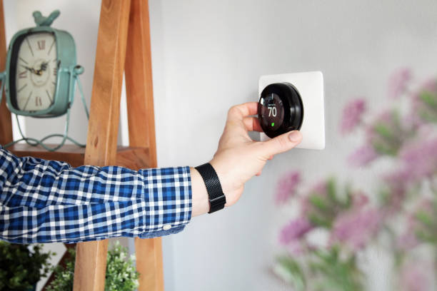 Man is Adjusting a temperature on the thermostat in the living room. Man is Adjusting a temperature on the thermostat in the living room. thermostat stock pictures, royalty-free photos & images