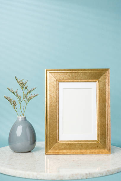 blank luxury gold photo frame with flower vase decor on stone table wtih blue background stock photo