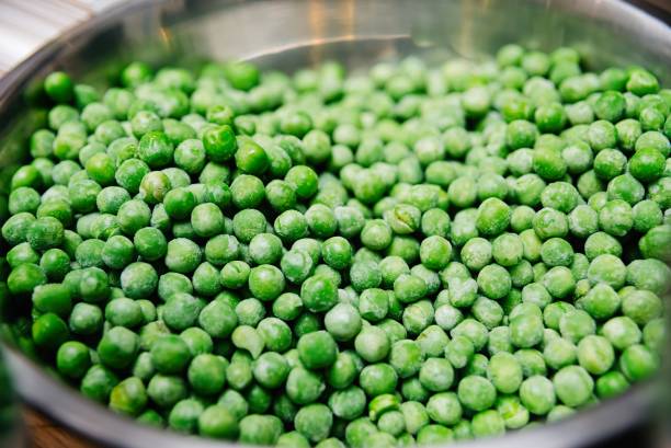 frosted green peas in a metal bowl stock photo