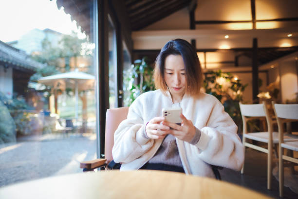 istock Chinese lady using mobile phone to surf the Internet in coffee shop 1455896449