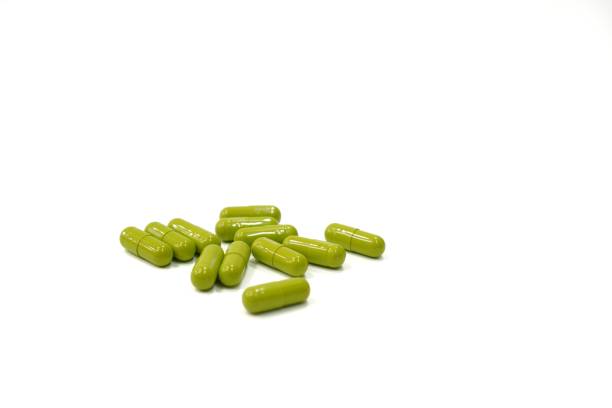 istock Image showing green herbal medicine capsules on a white background, close up. 1455898472