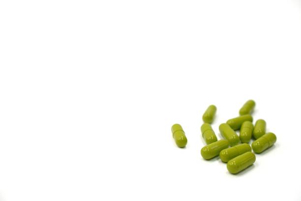 istock Image showing green herbal medicine capsules on a white background, close up, copy space. 1455898476