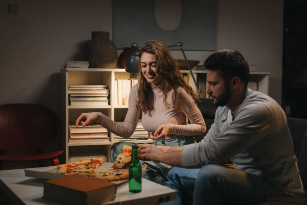 istock couple having fun eating pizza at home 1455900141