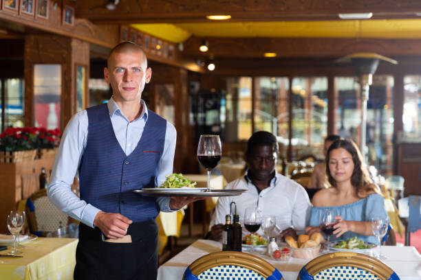 istock Professional young smiling waiter holding serving tray 1455901181