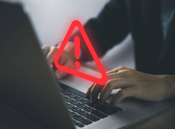 istock Businessman using laptop showing warning triangle and exclamation sign icon Warning of dangerous problems Server error. 1455901201