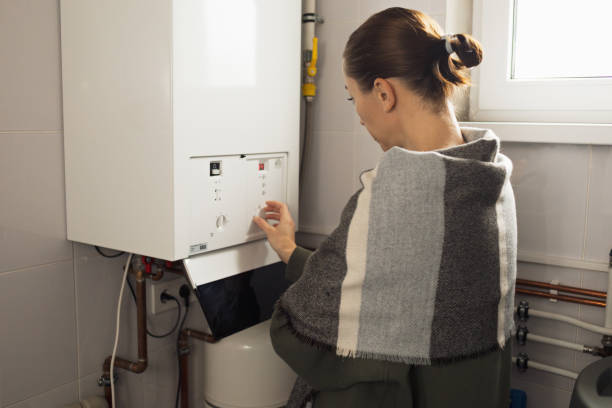 A woman reduces the power of the gas boiler in her home due to an energy crisis stock photo