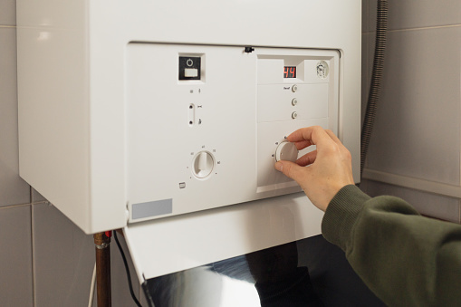 A woman reduces the power of the gas boiler in her home due to an energy crisis