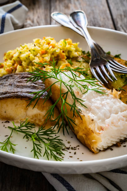 istock Fried halibut and potatoes with cabbage salad on wooden table 1455902130