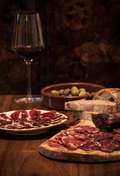 prosciutto iberico e salumi, olive, pane e bicchiere di vino rosso su tavola di legno - tapas food spain gourmet foto e immagini stock