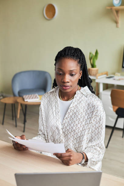 istock Black young woman using laptop in minimal office setting 1455902562