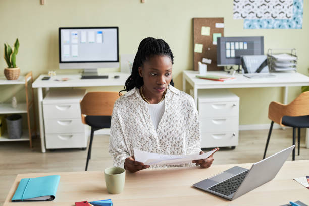 istock Black young woman using laptop working at desk in cozy office setting 1455902590